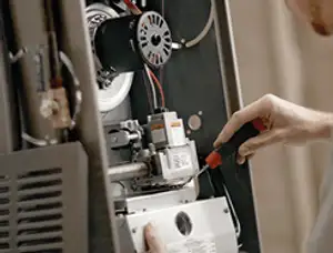 Furnace repair technician inspecting internal components and wiring in Fort Worth, TX
