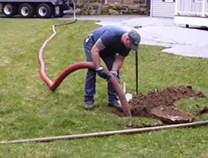 Septic pumping technician servicing a residential septic tank with a vacuum hose in Fort Worth, TX