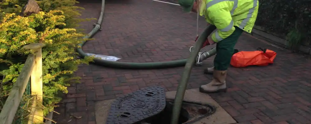 Septic tank cleaning technician servicing a septic tank with a vacuum hose in Fort Worth, TX